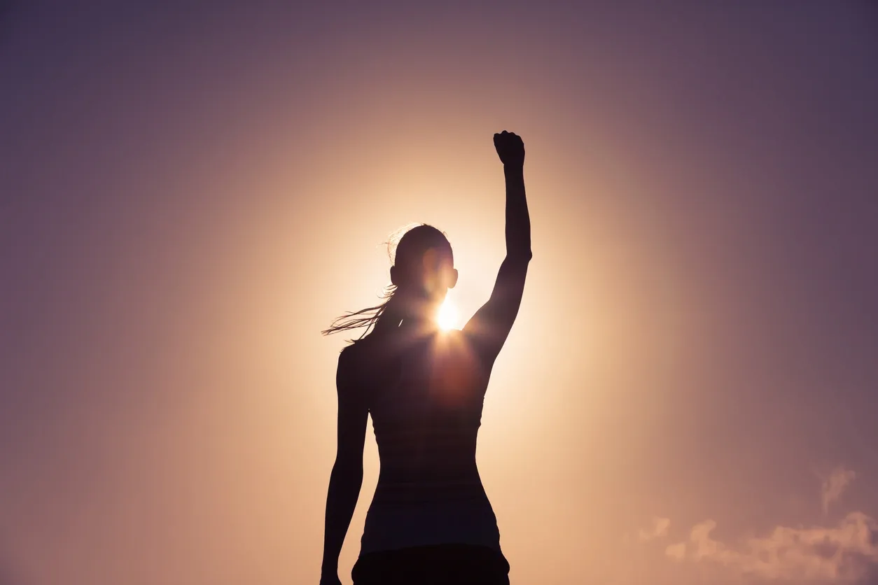 Silhouette of women with arm raised in the air feeling confident and triumphed with her CFS recovery through pacing. 