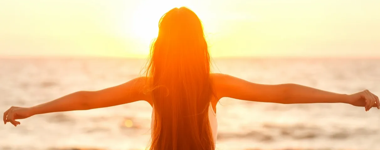 Image of women facing the sun, with arms stretched out to the sides. Image is representing a person with CFS feeling good after pacing themselves. CFS pacing toolkit: the pacing confident method.