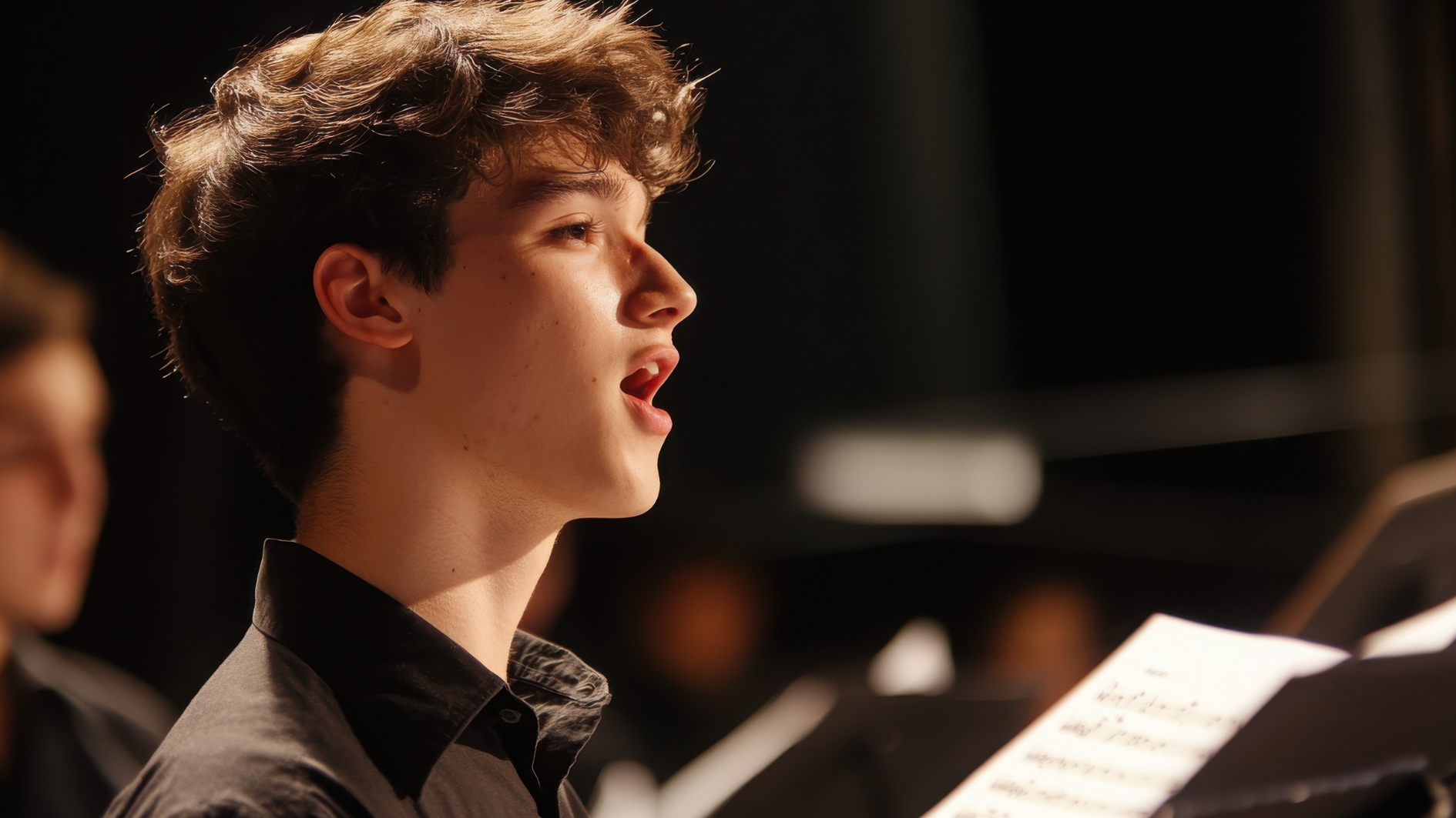 A young teen singing on stage with music