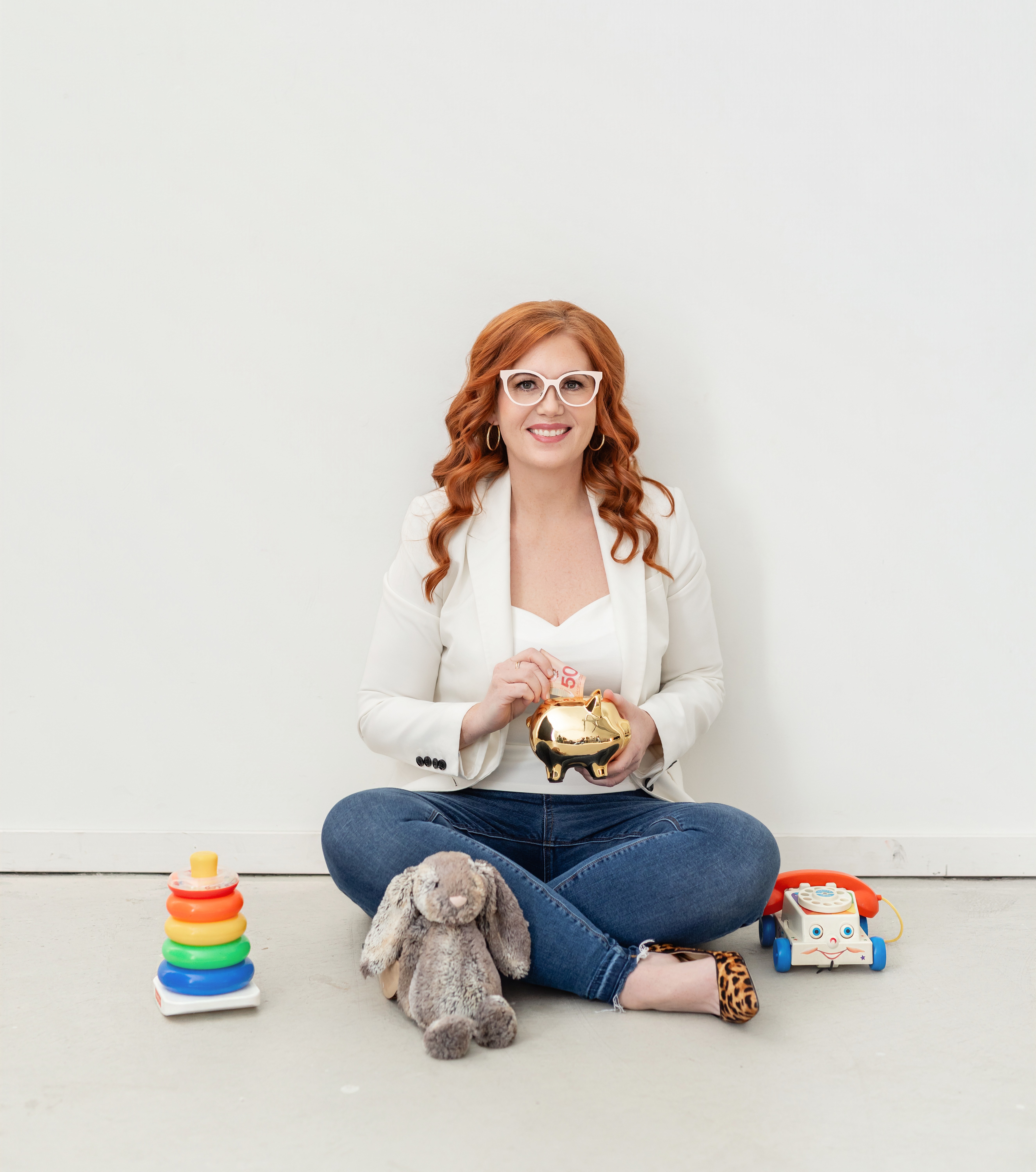 redhead woman sitting on floor with piggy bank