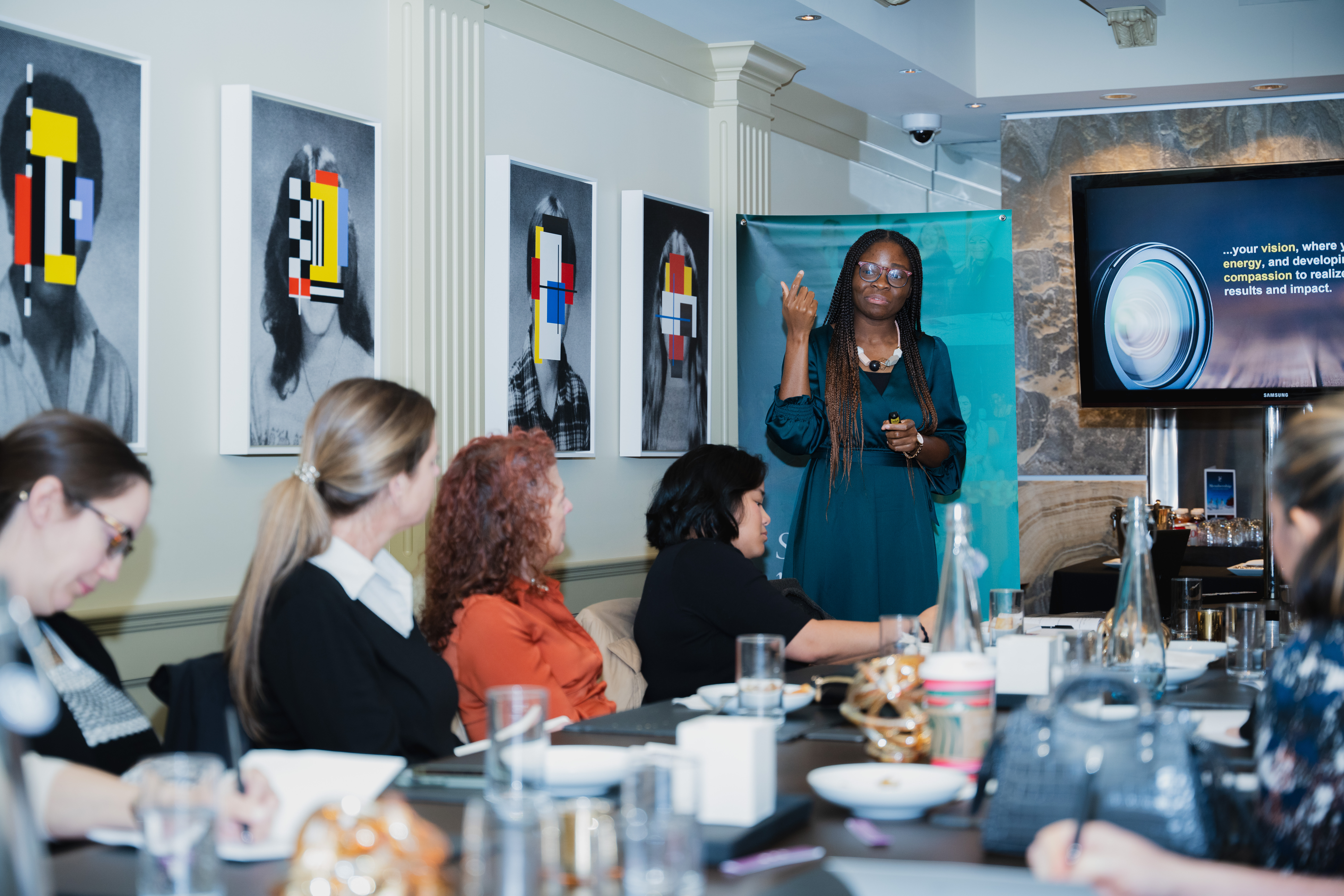 Image of Precious Ile speaking to a room of senior female executives and leaders.