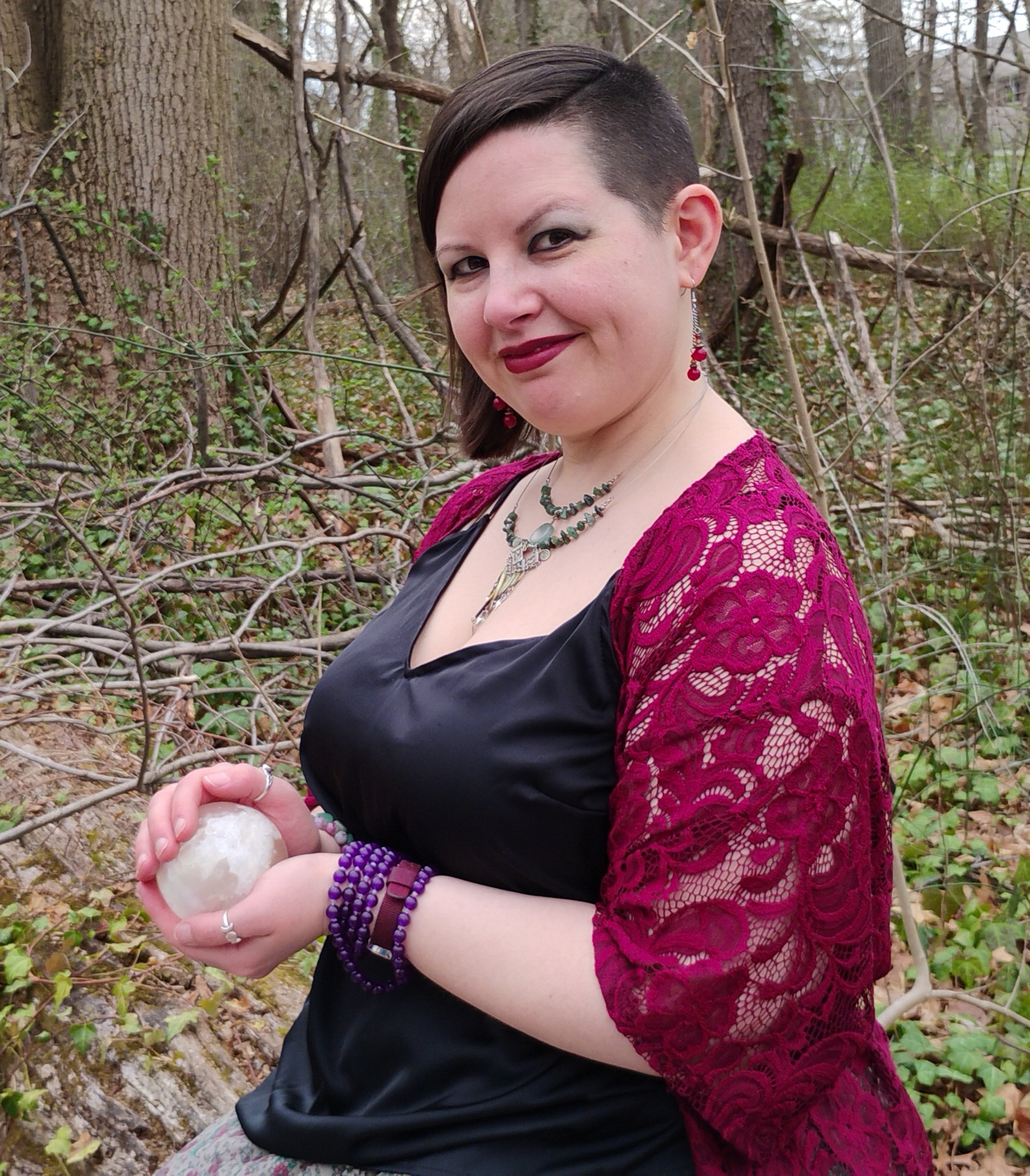 Photograph of Evylyn Rose in the woods holding a selenite sphere