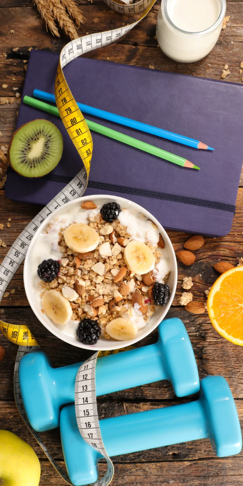 Weights, medals and healthy food on a wooden table.