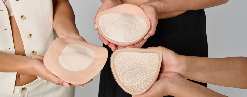 3 amoena breast forms being held by women's hands