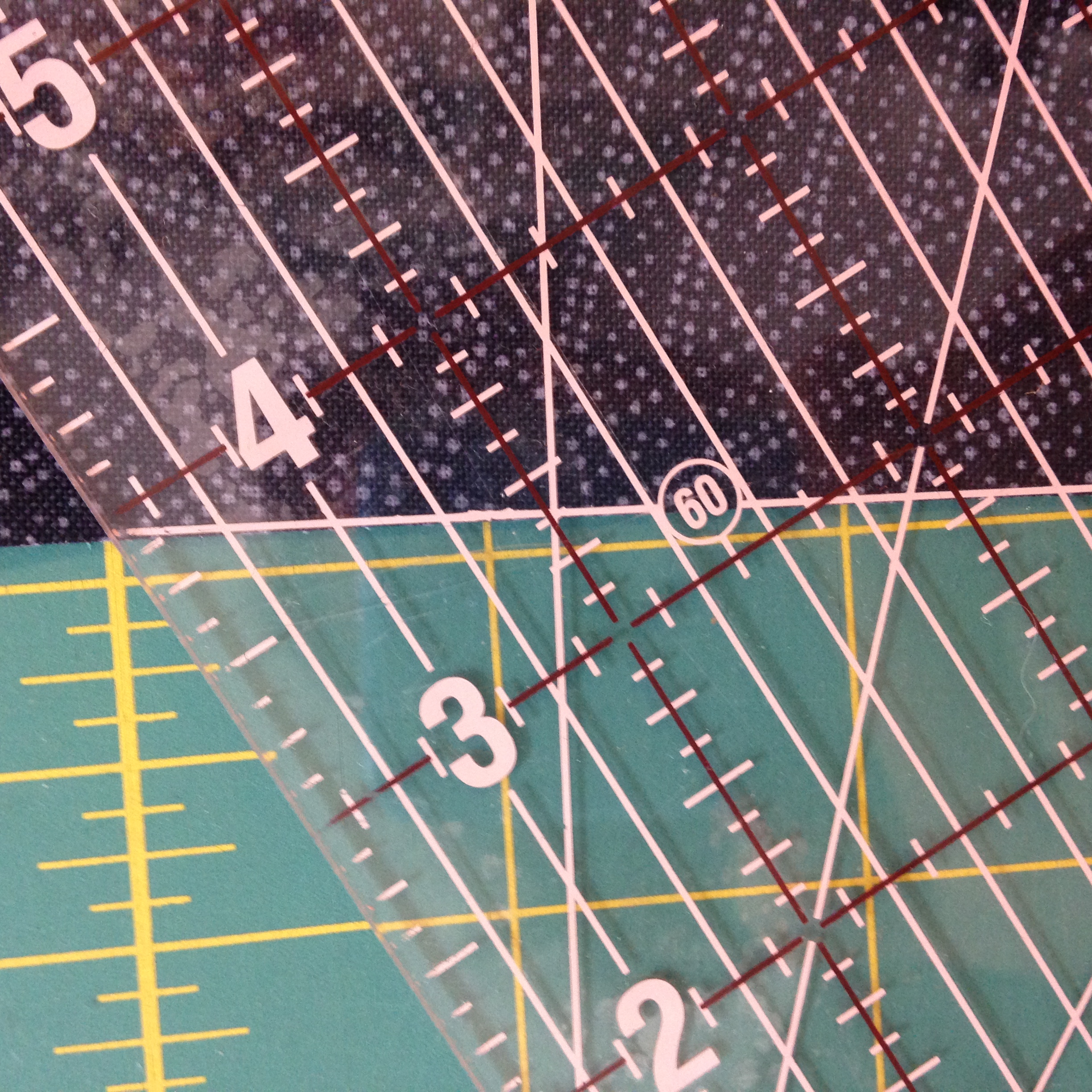 close up of quilting ruler with 60-degree line over the edge of a piece of dark blue fabric