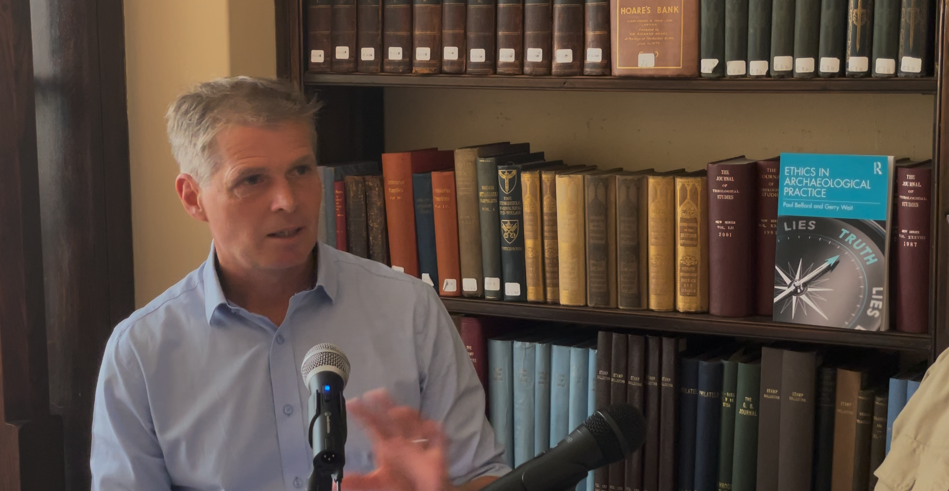Dr Paul Belford speaking in front of a bookcase