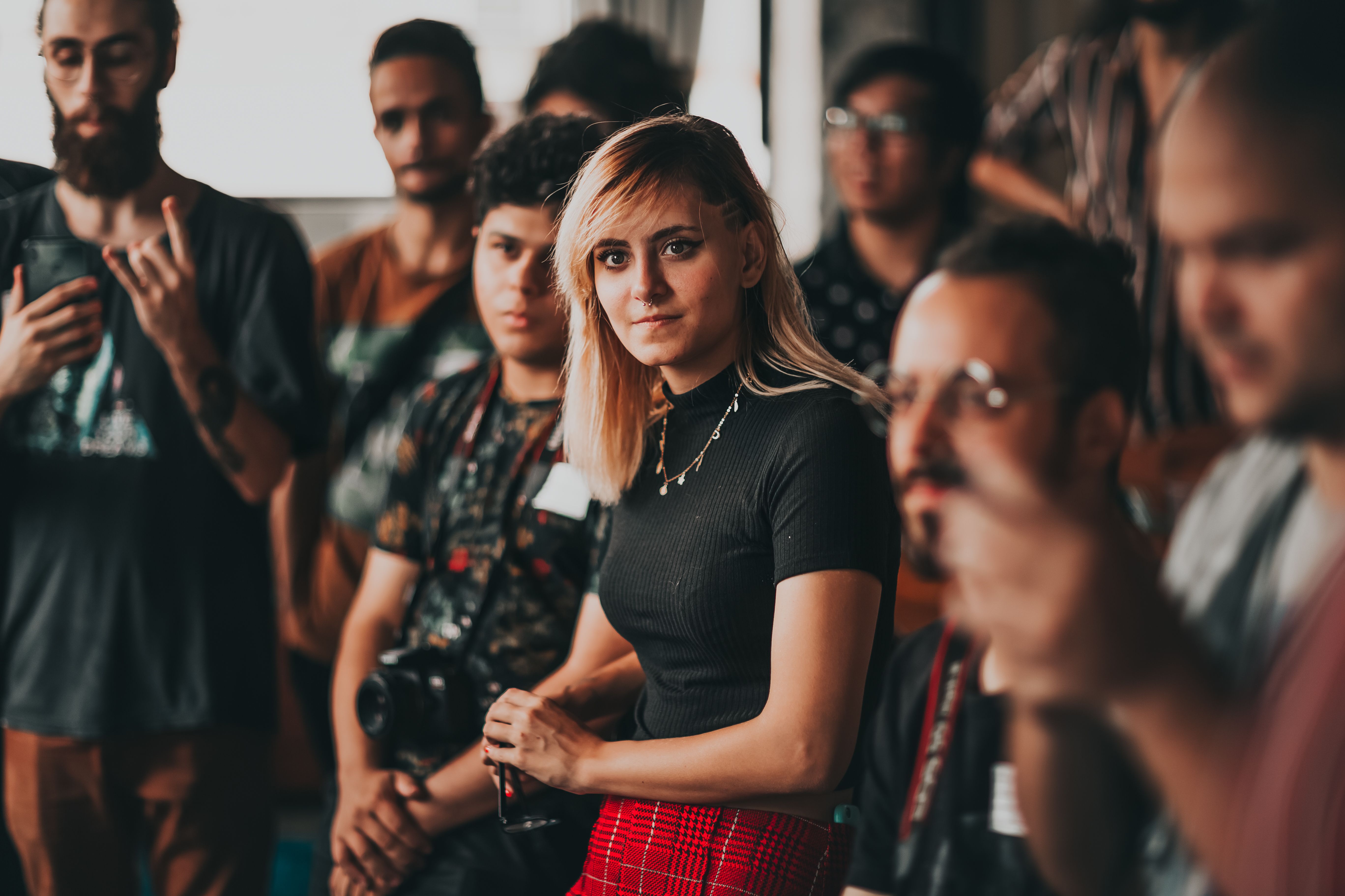 Crowded group of diverse individuals and in the center we can most clearly see one woman looking towards the camera.