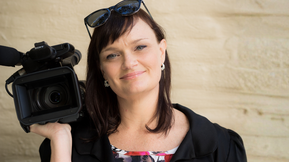 Headshot of Monica, the IGNITION SA program designer, holding a video camera.