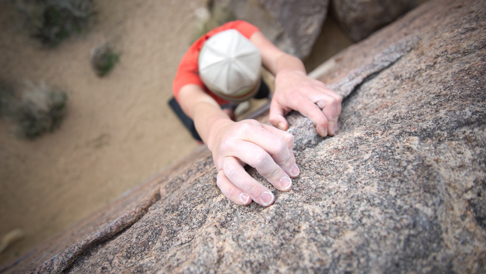 Close-up of a climber gripping a rock face while ascending a steep climb.