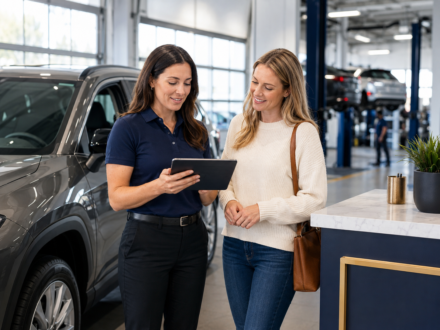 Automotive service advisor explaining vehicle inspection findings to a customer using a tablet in a modern service drive.