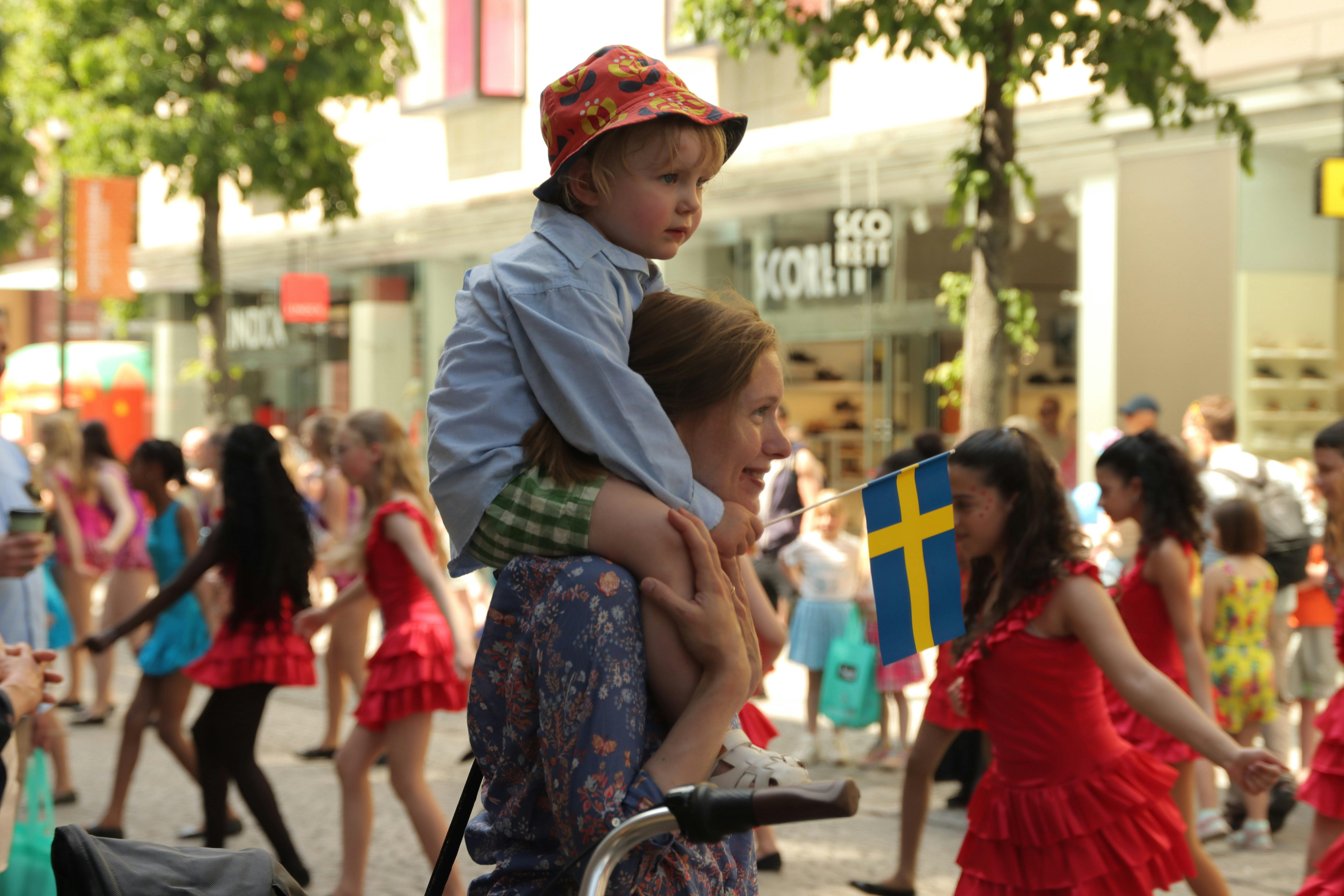 Woman with a child on her shoulders enjoying a parade