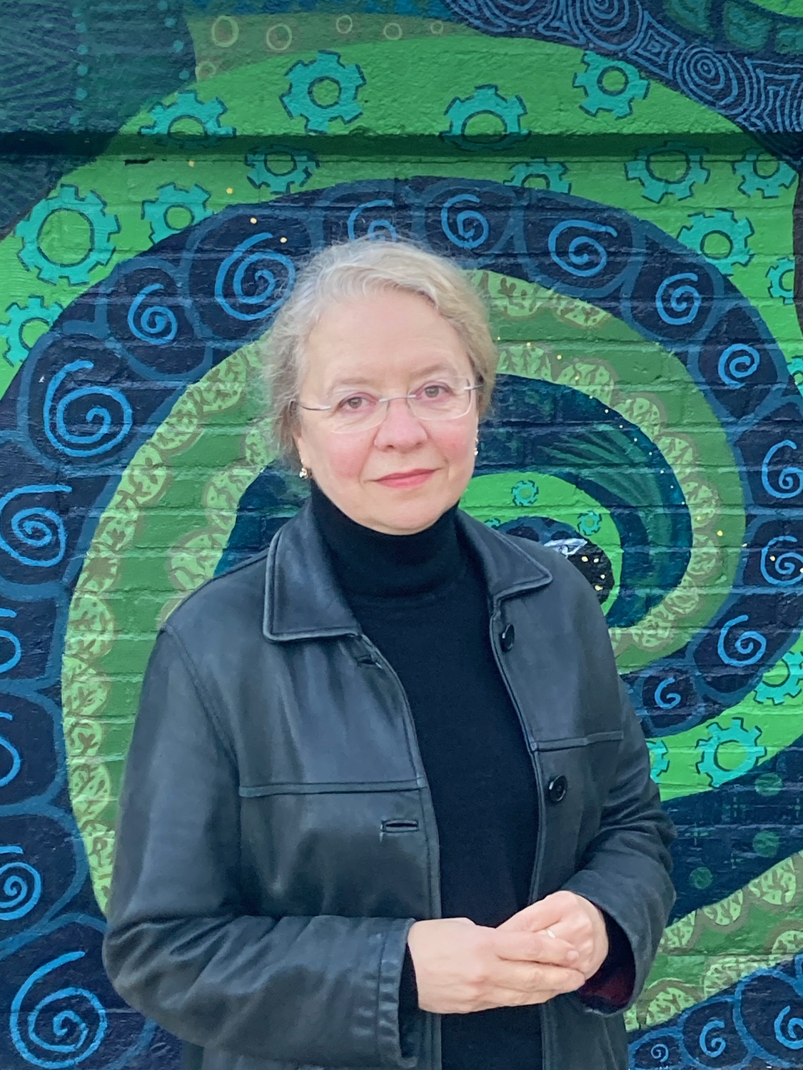 Alexandra G. Bowers poses in front of a green mural.
