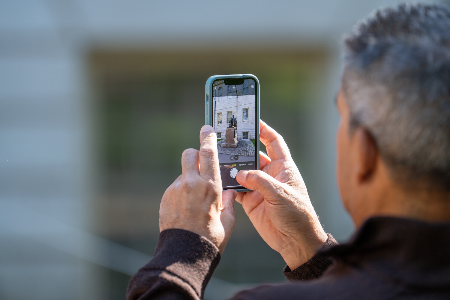 A tourist takes a photo of the John Harvard statue.