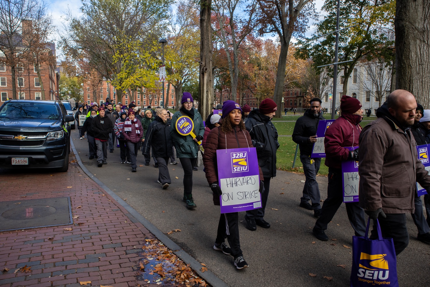 Custodians represented by the Service Employees International Union 32BJ march through Harvard Yard on Monday, the first day of their strike.