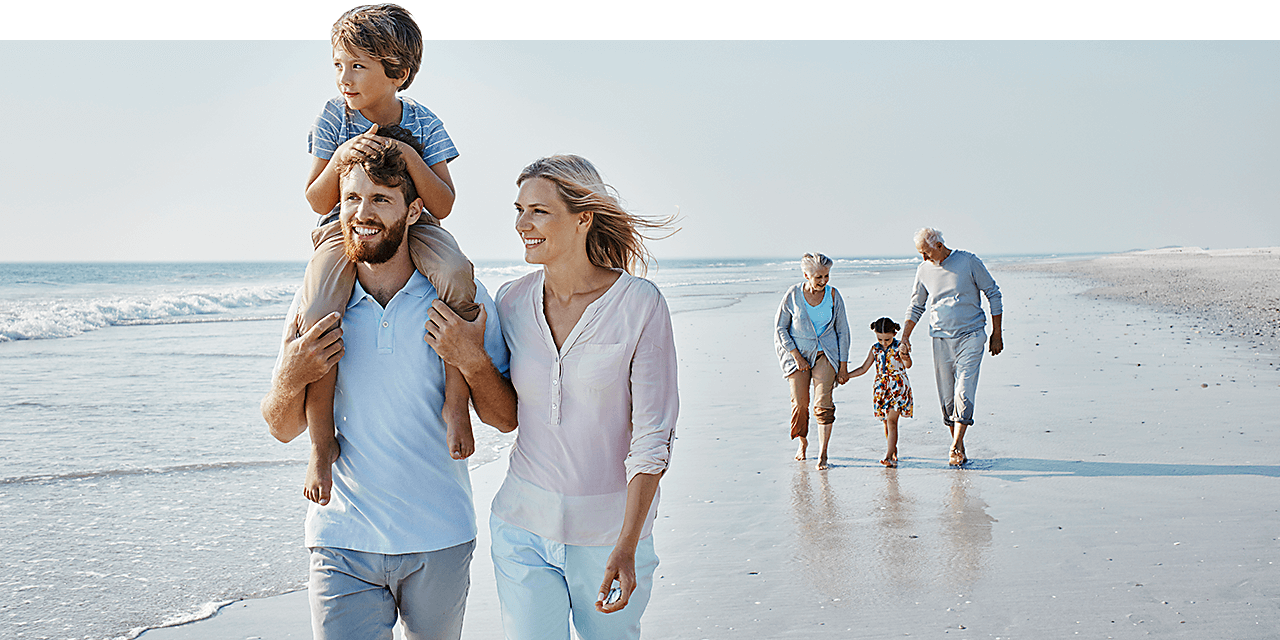 A multigenerational family walking along the beach.