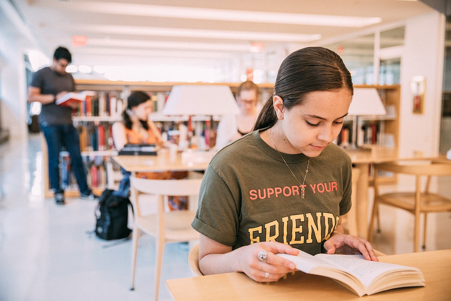 People read books in the University Center llibrary, with a seated student in the foreground.