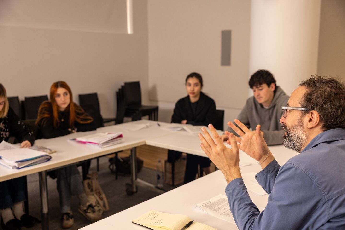 Four students engage in discussion with a faculty member in the classroom.