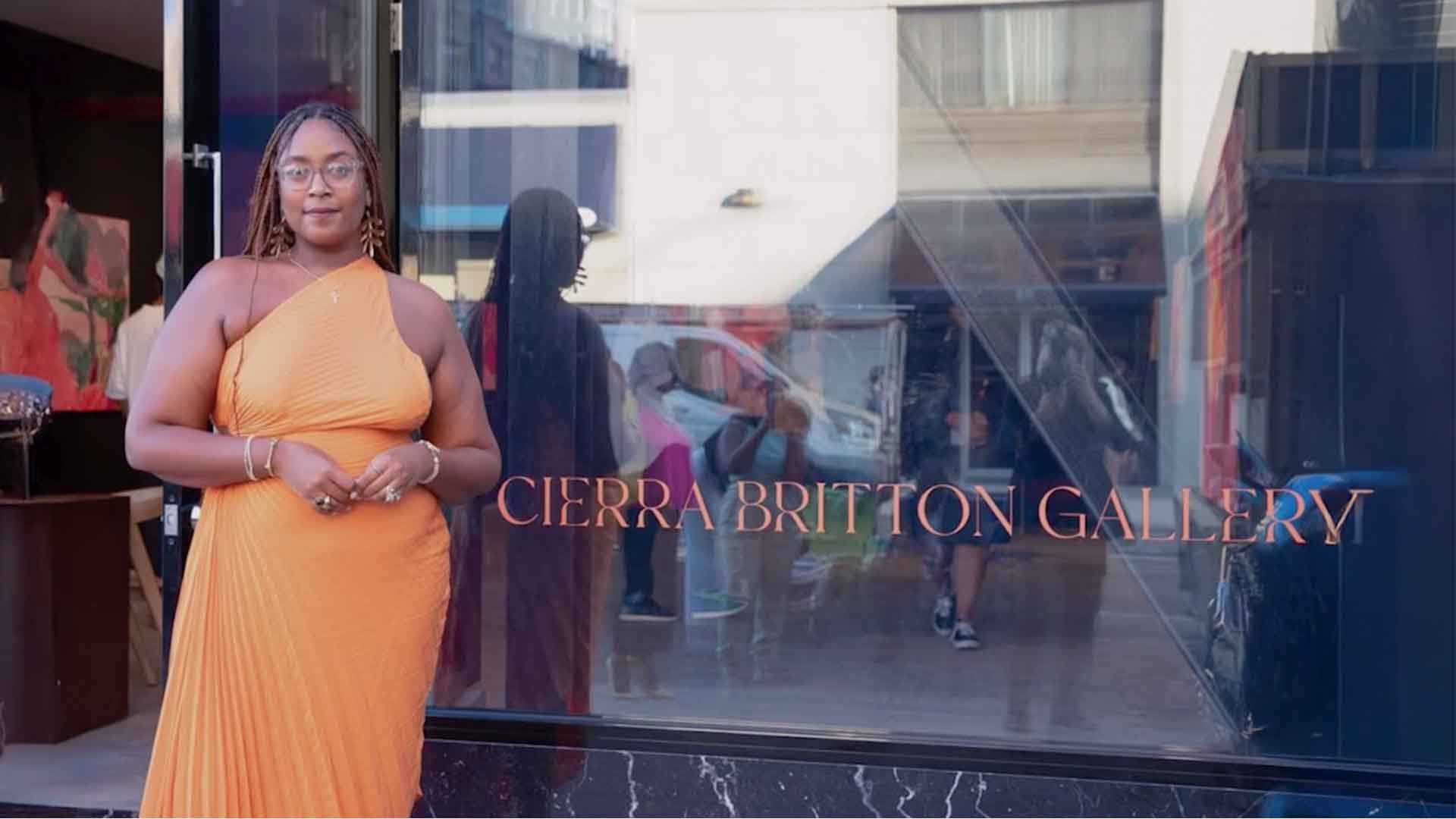 Cierra Britton stands in front of the street-facing window of her gallery. On the window are the words, "Cierra Britton Gallery."