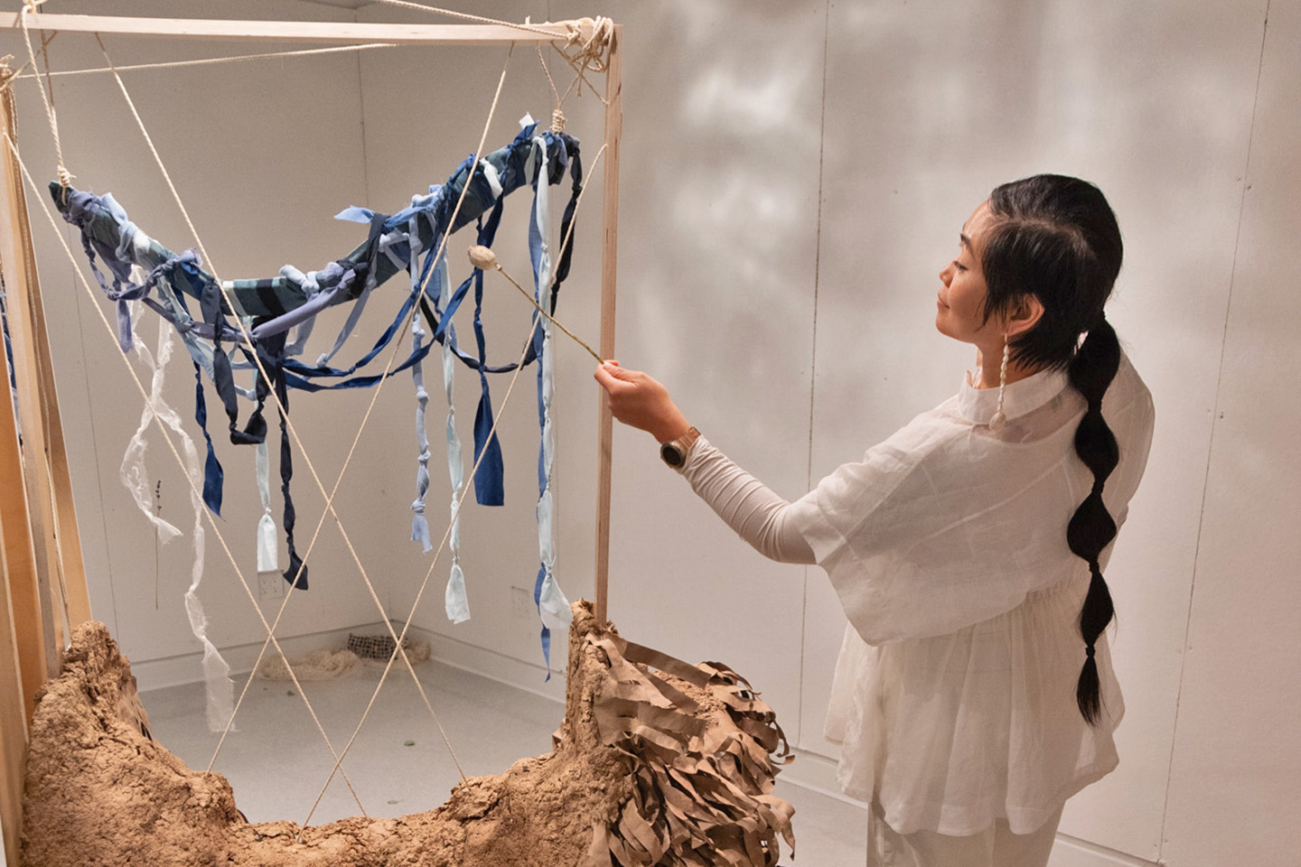 Faculty carefully interacts with a large abstract multimedia installation that hangs from the ceiling.