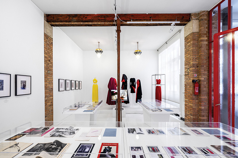 Curating Research Lab—a gallery with images displayed on walls and in tables with clothing displayed on mannequins in the background.