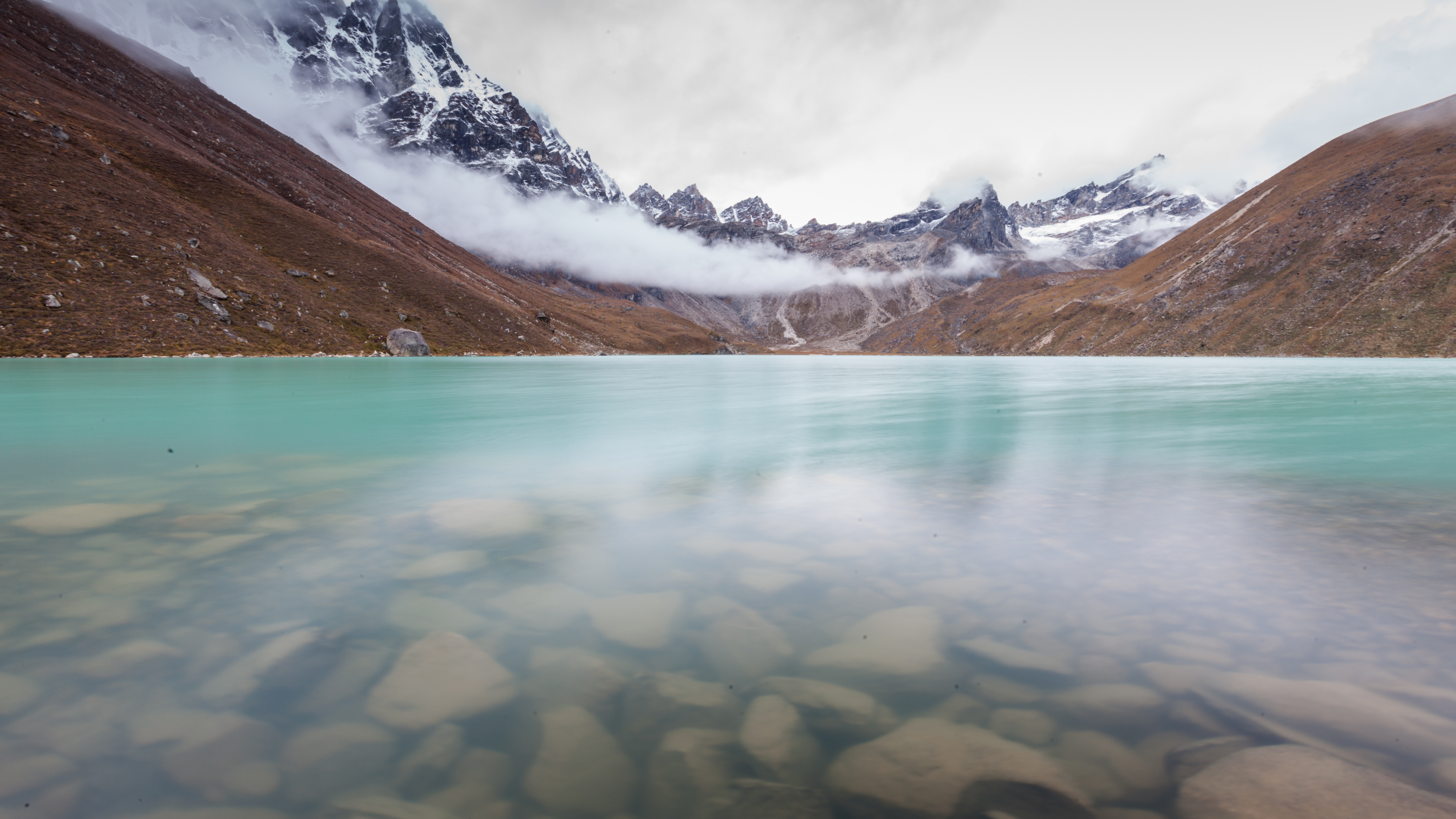 Green lake between mountains in cloudy day