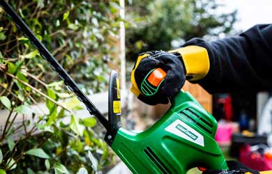 Gloved hand using a hedge trimmer