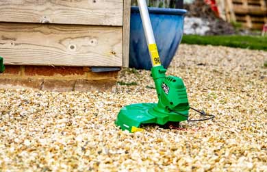 Grass trimmer standing on some shingle
