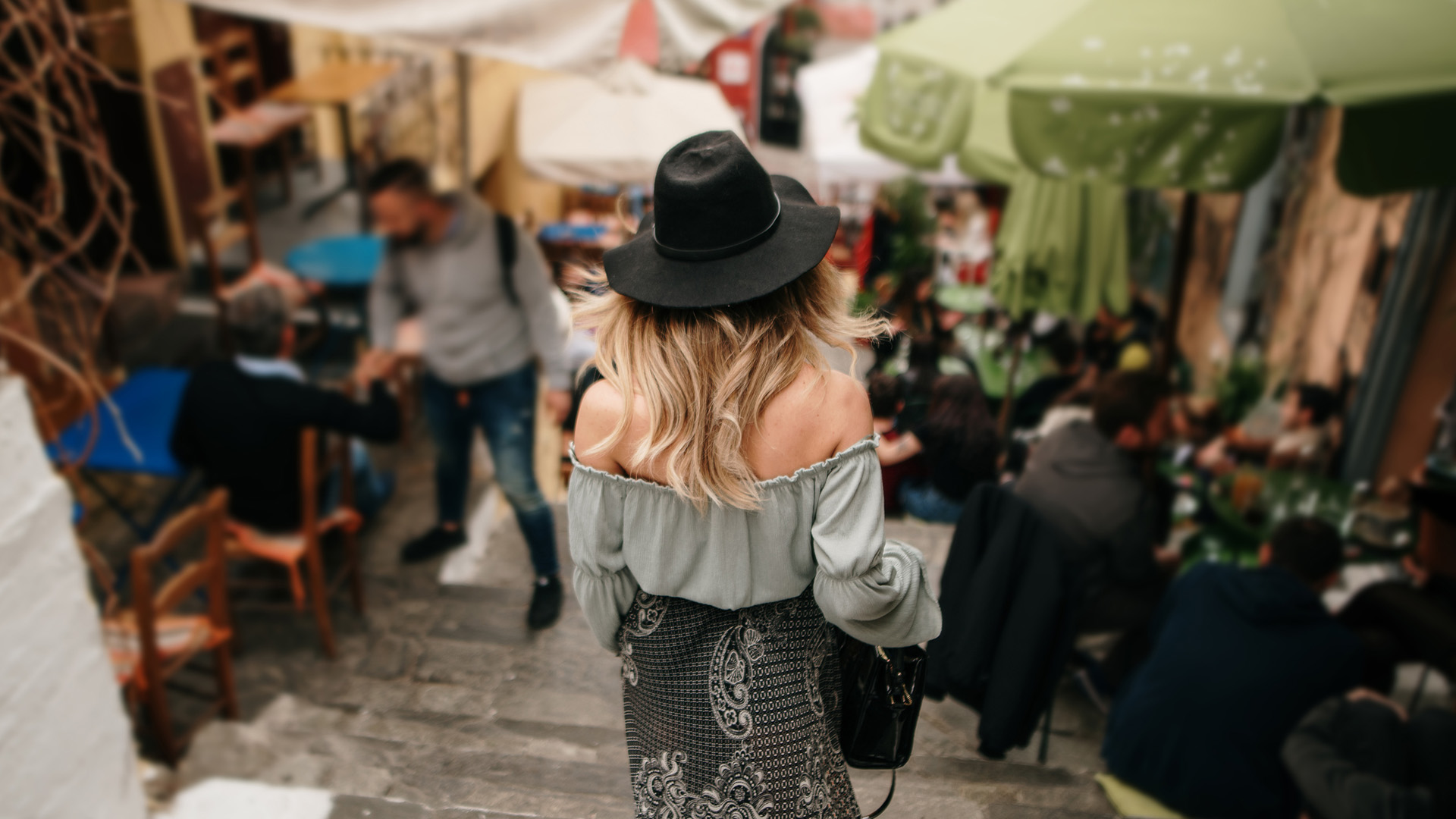 A woman walks down the steps of Plaka alongside restaurants in Athens, Greece