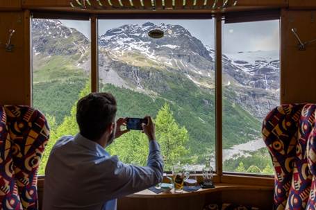 A person taking a picture of a mountainAI-generated content may be incorrect.