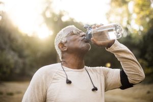 older man drinks water after a workout