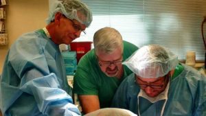Surgeons dressed in scrubs in an training room.