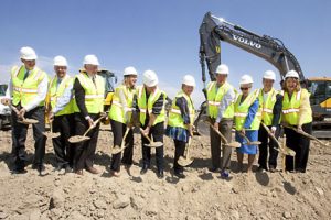 A photo of 10 people as they prepare to dig up the first shovels of dirt, breaking ground on UCHealth Greeley Hospital.