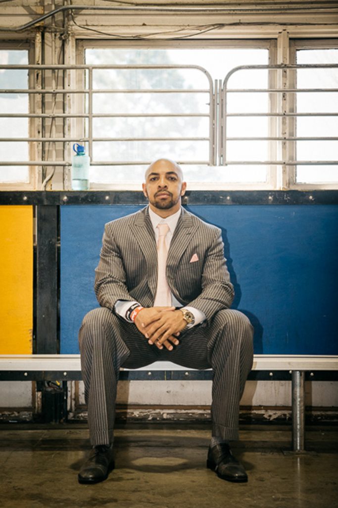Bo Scaife, wearing a suit and tie, sitting on a bench.