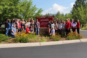 Photo of several workers at UCHealth Yampa Valley Medical Center. They're grouped around a new sign showing that the hospital is now part of UCHealth.