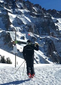 Jonathan Greenspan carries his skis, headed higher than a lift will take him.