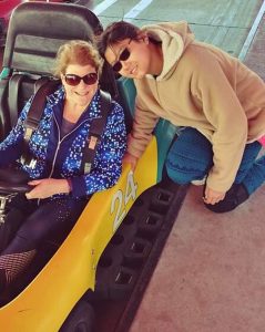 Cella and Lilly Roberts enjoy having fun together. Here they ride in a race car at an amusement park.