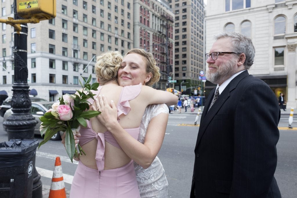 Sisters Laura Zirkle, left, and bride-to-be, Rachel Zirkle, embrace in one last hug before walking down the aisle. Their father, Doug Zirkle, smiles watching the two. Photo by Elaine Cromie for UCHealth.