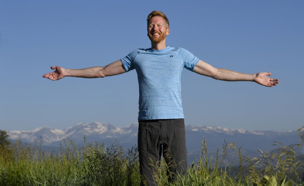 Jonathan Proctor celebrates feeling much better after getting surgery for a condition called pectus excavatum. Here, Jonathan holds his arms out to show how easily he can breathe. Behind him, you see the snow-capped Rockies.