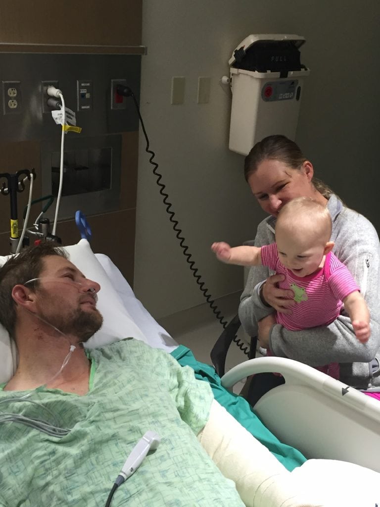 Archie Chant in his hospital bed. He's immobile as his wife and baby daughter visit him.