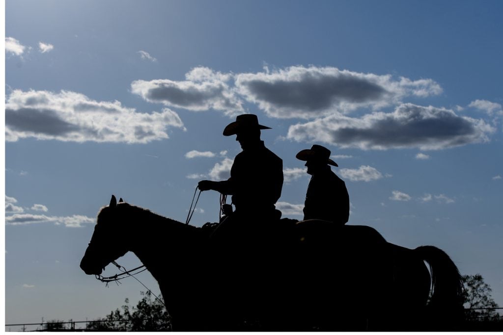 A silhouette shows two men on horseback together.