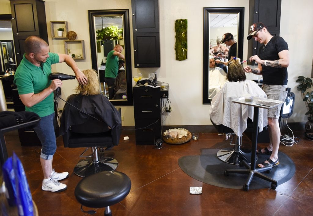 Newly married, Stephen Estrada and Kenley Erskine also work side by side in a hair salon. Here they are both doing hair for women.