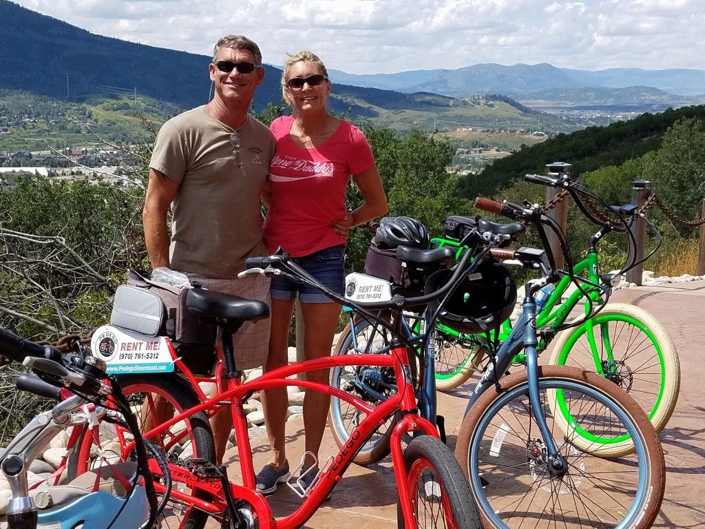 Scott and Ramona Rudis pose for a photo behind bicycles | Bike helmet safety | UCHealth