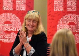 Chief nursing officer smiles and clasps hands as recognition is announced.