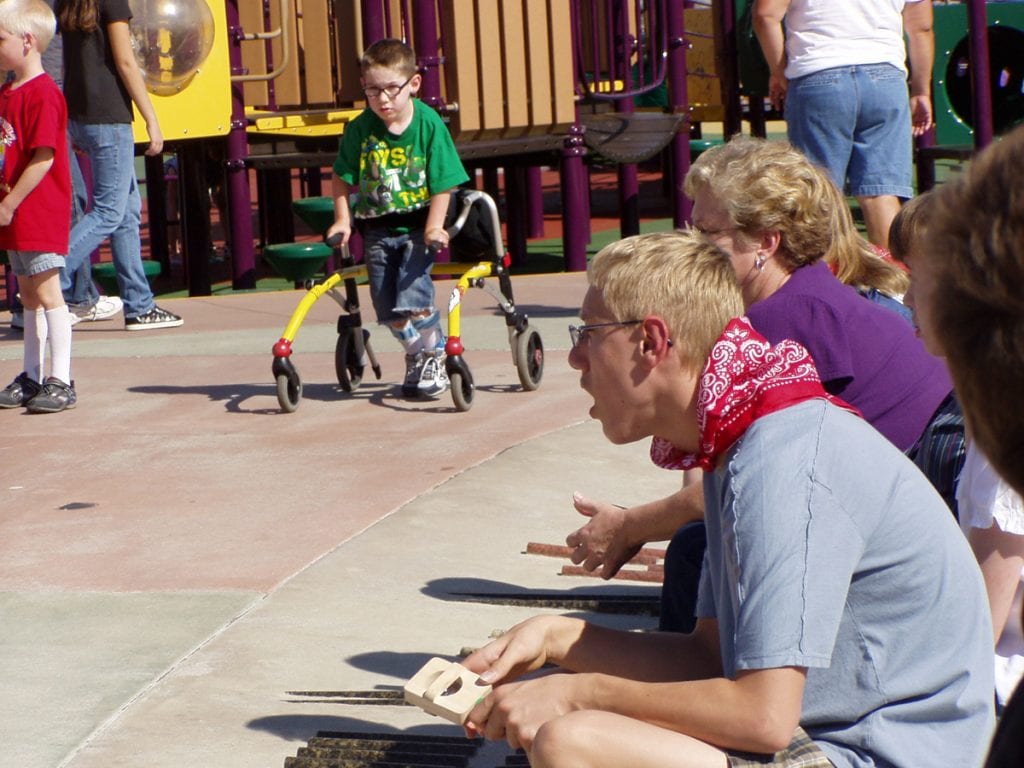 A boy using a walker plays at Inspiration Park in Fort Collins. In the foreground, some special needs teens also play at the park. It was designed to be "universally accessible"