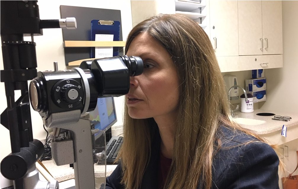 Pelak looks through eye exam equipment.