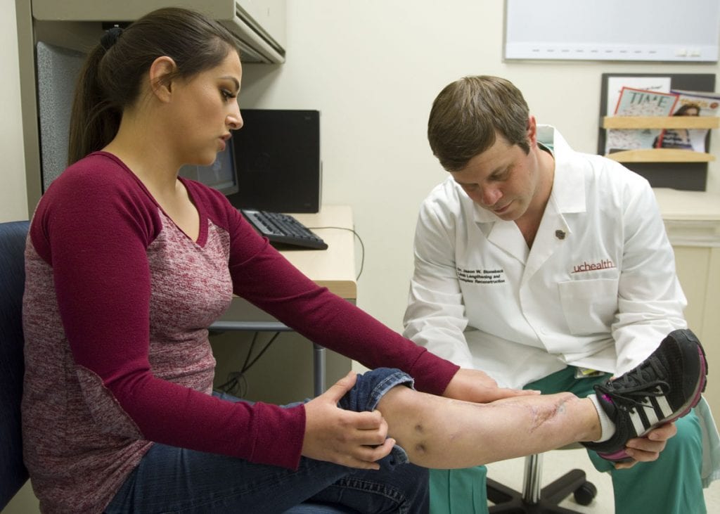 A physician examines a patient's injured leg.