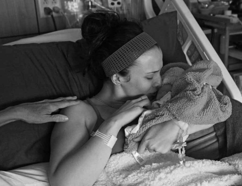 a photo shows a mom kissing her infant son who is wrapped in a blanket. He died from a fatal disease soon after birth.