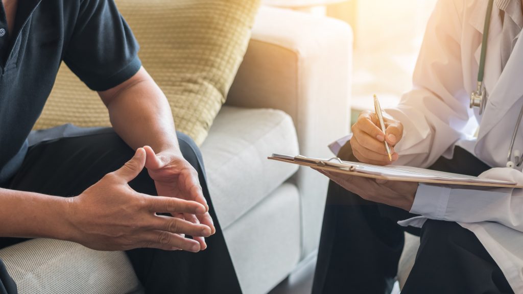A male patient speaks with a physician in this photo.