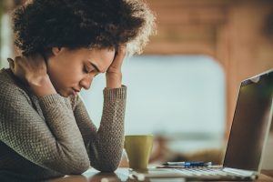 A women looks like she doesn't feel good sits in front of her computer, getting ready to call her online doctor.