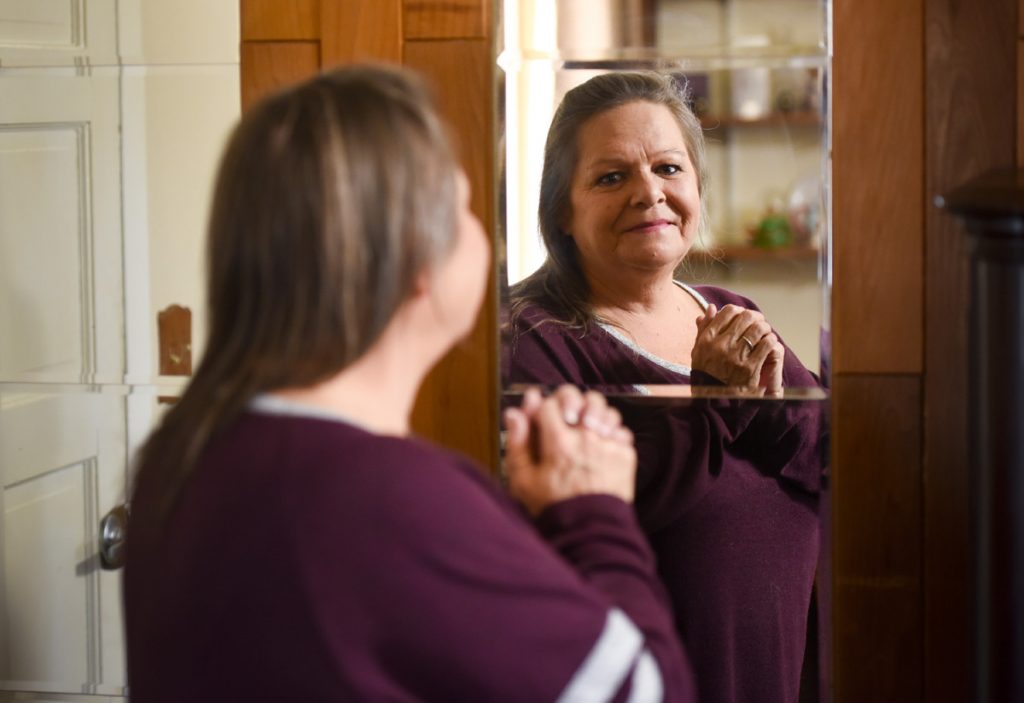 A formerly blind woman looks into a mirror to see her own face.